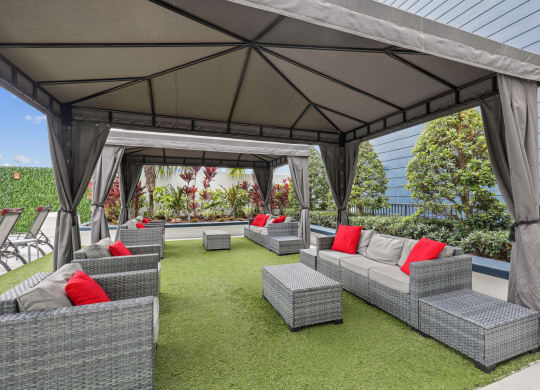 a lounge area with couches and chairs under a gazebo