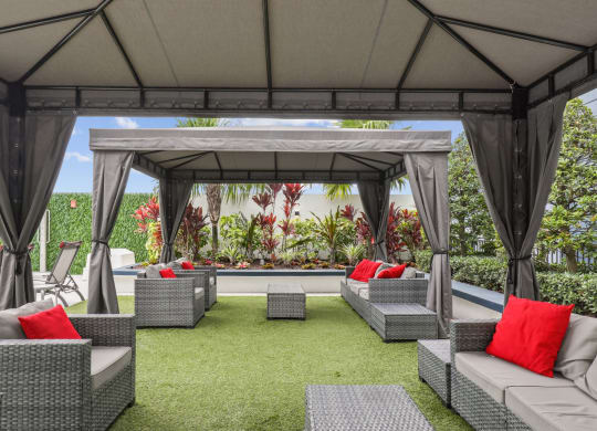 a lounge area with couches and chairs under a gazebo