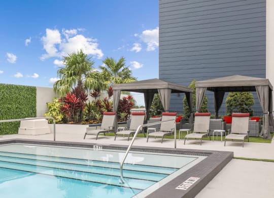 a swimming pool with lounge chairs next to a building