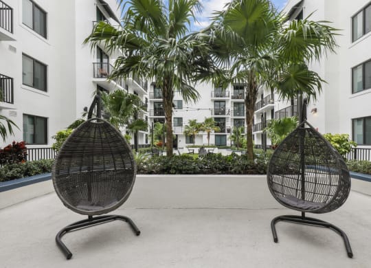 two chairs in front of an apartment building with palm trees