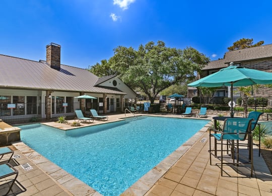 a pool with lounge chairs and umbrellas at the enclave at woodbridge apartments in sugar