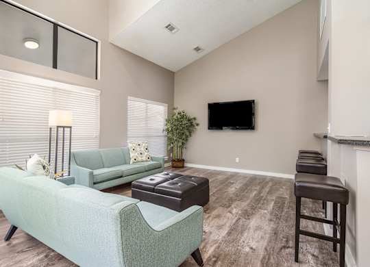 Clubhouse with a green couch and a flat screen TV mounted on the wall at Poplar Place Apartments