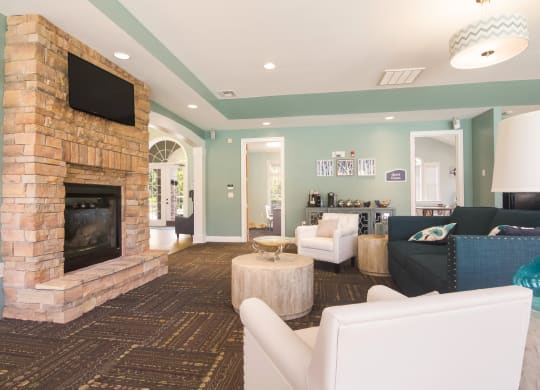Resident lounge area with couches facing a fireplace and TV at Angel Landing Apartment Homes in Pensacola, FL