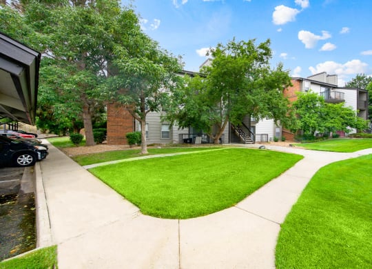 Walkways with beautiful landscaping from covered parking leading to our apartment buildings at Greensview in Aurora, CO