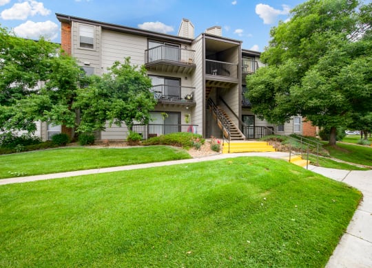 View of one of our apartment buildings with stairs and private patios and balconies at Greensview Apartments in Aurora, CO
