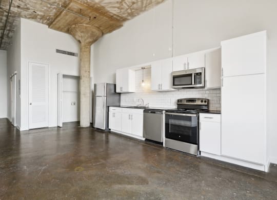 Continental Building loft kitchen with stainless steel appliances and white cabinets | Continental Lofts Building from Deep Ellum Lofts in Dallas, TX