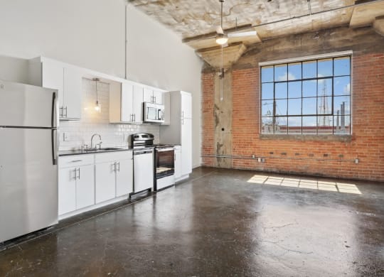 Kitchen from loft with brick wall, white cabinetry, and stainless steel appliances | Continental Building Lofts from Deep Ellum Lofts in Dallas, TX