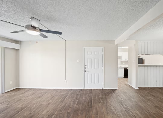 an empty living room with a ceiling fan