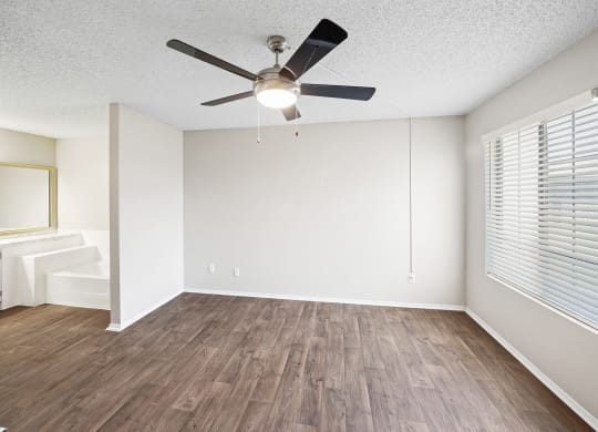 an empty living room with a ceiling fan