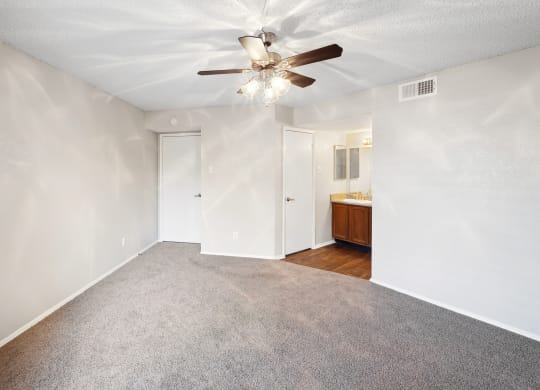 a bedroom with white walls and a ceiling fan
