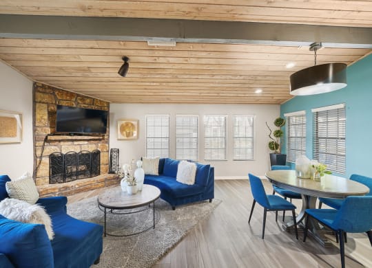 a living room with blue couches and chairs and a fireplace with a tv above it