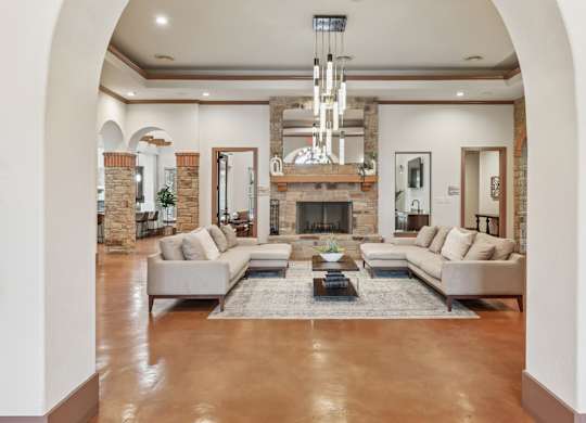 A large, modern resident lounge with a fireplace and a chandelier at Creekside on Parmer Lane Apartments in Austin, TX
