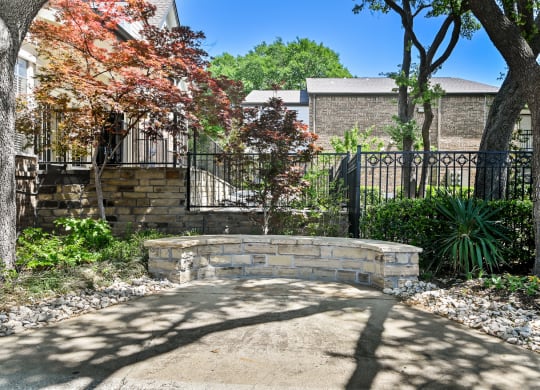 a retaining wall with a stone bench in front of a black wrought iron fence