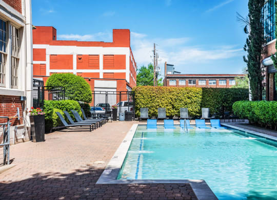 a swimming pool with chaise lounge chairs and a building in the background