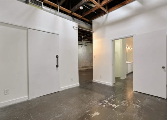 an empty room with white walls and doors and a door to a bathroom