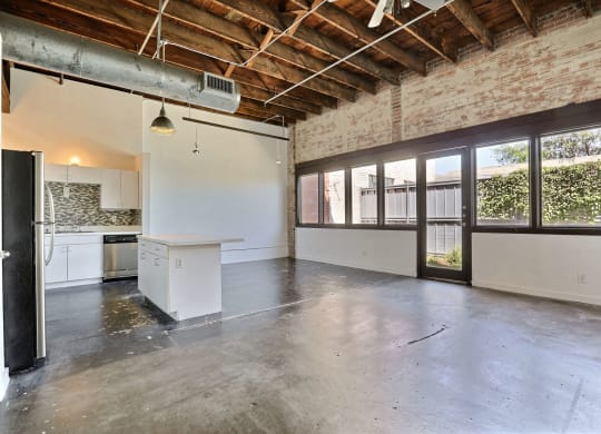 an empty room with a kitchen and a large window