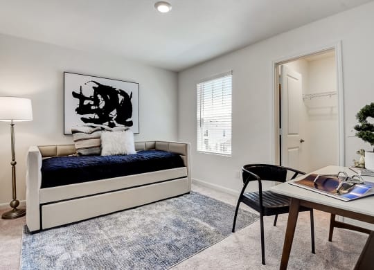 a bedroom with a study desk, a chair and window with a closet