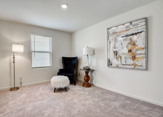 a bedroom with a chair and a lamp and a painting on the wall
