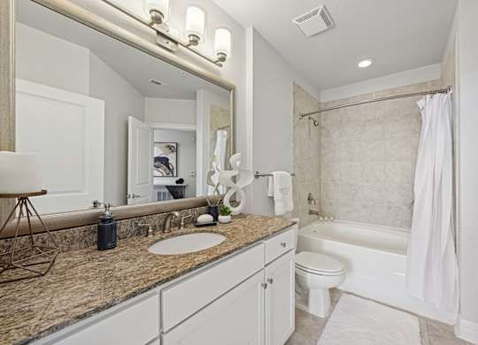 Model bathroom with granite countertop and jacuzzi tub at Dominion Post Oak apartments in Houston, TX