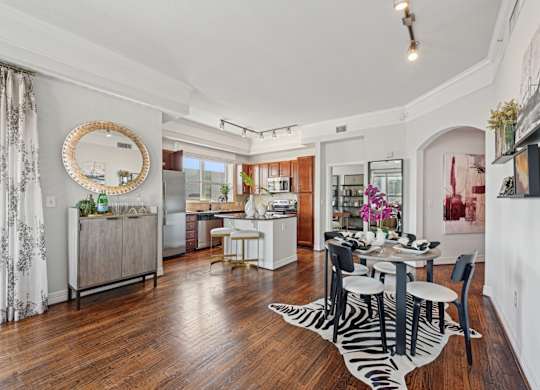 Model apartment dining room with a zebra print rug and a round mirror on the wall at Dominion Post Oak apartments in Houston, TX