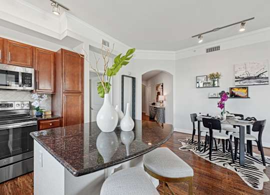 A kitchen with a black granite countertop and maple colored cabinets at Dominion Post Oak apartments in Houston, TX