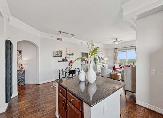 Model kitchen with a dark counter top and wooden floors at Dominion Post Oak apartments in Houston, TX