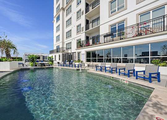 Our swimming pool in on the rooftop patio with blue chairs around it at Dominion Post Oak apartments in Houston, TX