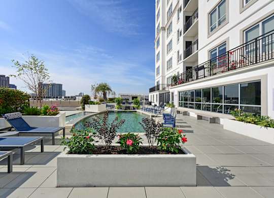 Our rooftop pool with a planter box with flowers and chairs at Dominion Post Oak apartments in Houston, TX