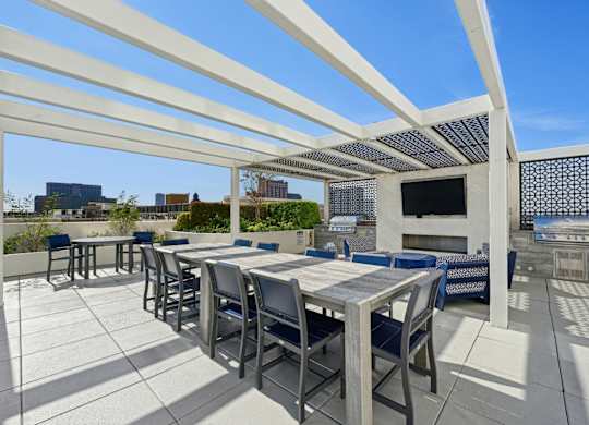 Outdoor grilling area with large dining table and two BBQ grills at Dominion Post Oak apartments in Houston, TX