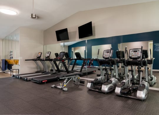 fitness center filled with cardio equipment and flat screen televisions at Dunwoody Pointe in Sandy Springs, GA