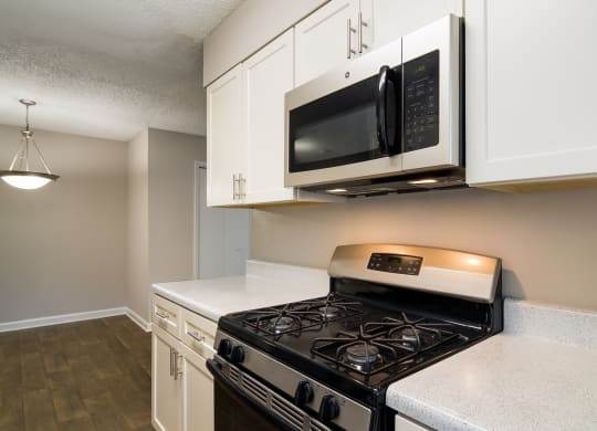 a kitchen with white cabinets and a black stove top oven at Dunwoody Pointe in Sandy Springs, GA