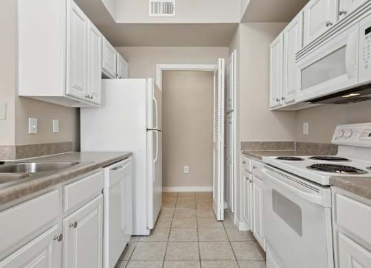 Edinburgh kitchen with white appliances and cabinets at Encore at Buckingham Apartments in Richardson, TX