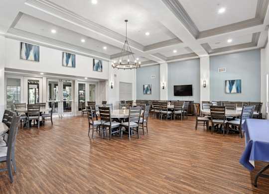 A large event room with a hanging chandelier and tables and chairs at Encore at Buckingham Apartments in Richardson, TX