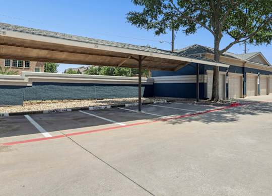 Reserved resident parking spots for compact cars with garages in the background at Encore at Buckingham Apartments in Richardson, TX