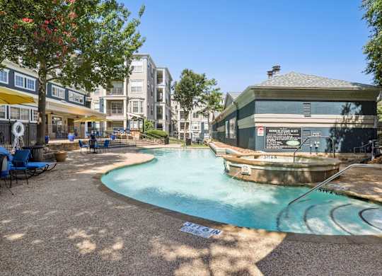 A sparkling swimming pool with apartment buildings in the background at Encore at Buckingham Apartments in Richardson, TX