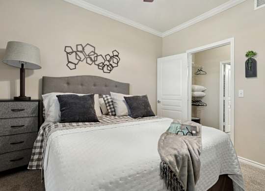 Windsor bedroom with a bed, closet, and wall decor at Encore at Buckingham Apartments in Richardson, TX