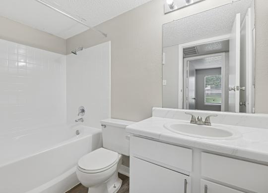 A white bathroom with a toilet, sink, and bathtub.