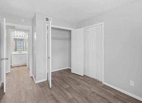 A3 bedroom with a white door, closet, and a wooden floor at Estelle Creek North Apartments in Irving, TX
