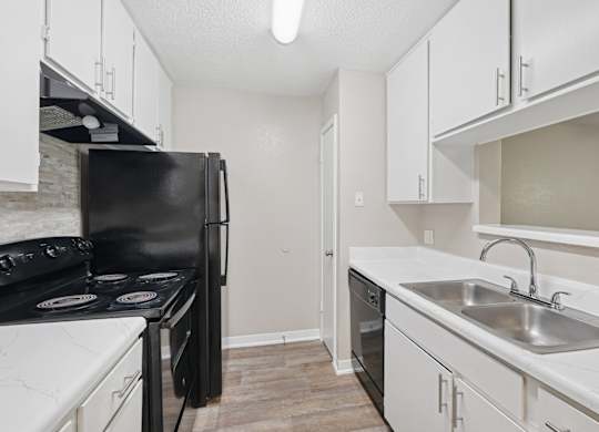 A kitchen with black appliances and white cabinets.