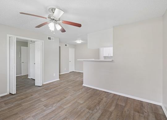 A room with a ceiling fan and wood flooring.