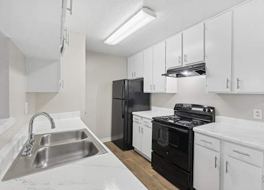 B1 kitchen with black appliances and white cabinets at Estelle Creek North Apartments in Irving, TX