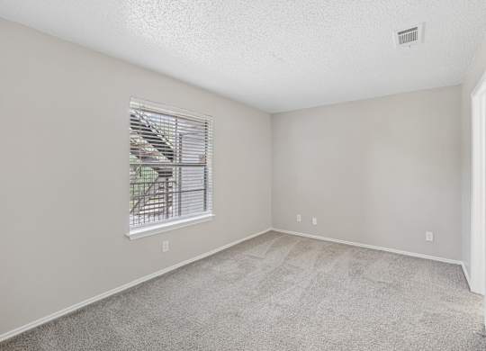 A room with a window and carpeted floor.