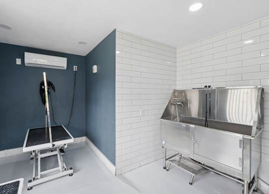 A room with a tiled wall and a stainless steel sink.