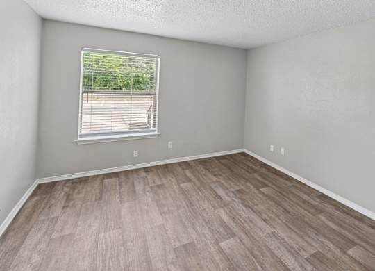 A room with a window and wooden flooring.