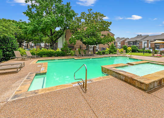 A swimming pool surrounded by a concrete floor and trees.
