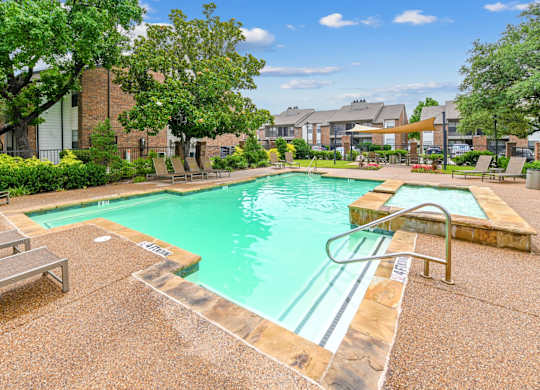 A pool surrounded by a concrete patio and a grassy area.