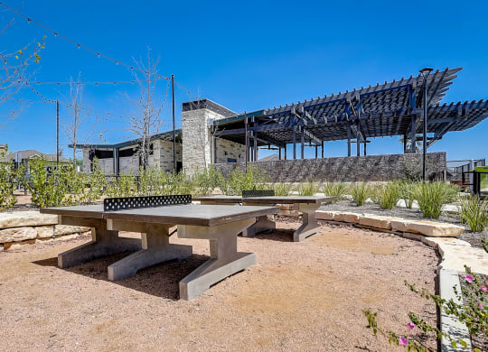 a picnic table with a ping pong table in front of a building at Beacon at Meridian, Texas