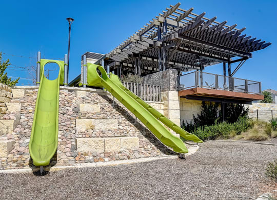 a green slide in front of a building at Beacon at Meridian, San Antonio, TX 78245