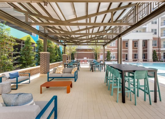 Shaded outdoor patio seating by the pool at Era Apartments in Denton, TX