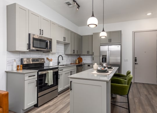 Model apartment kitchen with stainless steel appliances and quartz countertops at Era apartments in Denton, TX